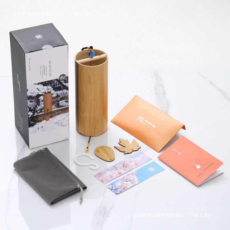 Bamboo wind chime pictured with a box, pouch, cord and decorative hanging pieces.