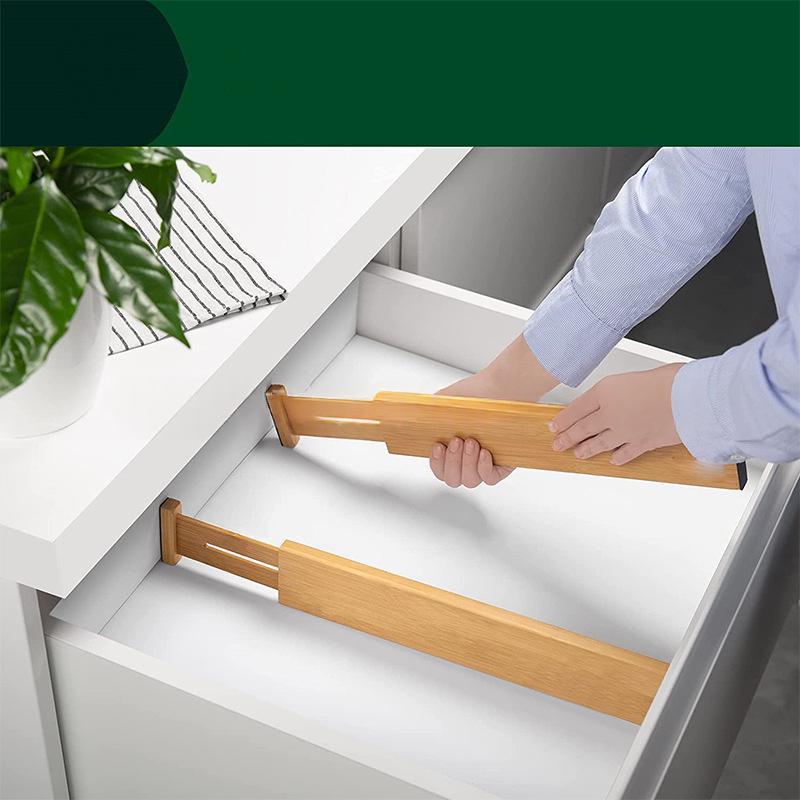 Hand placing an expandable bamboo drawer divider in a drawer